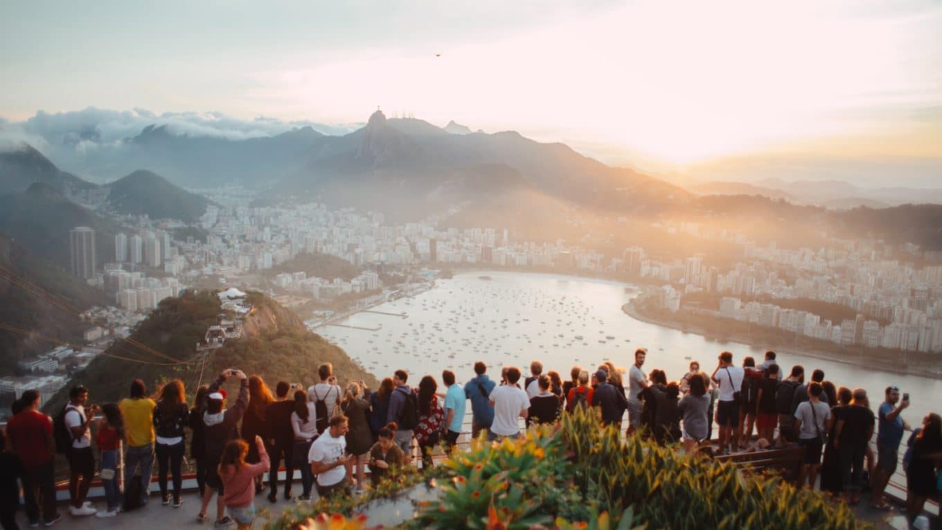 group of people standing facing lake view